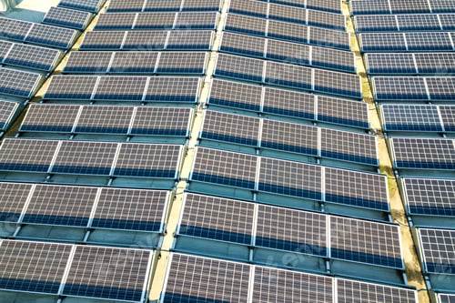 Preview: Aerial view of many photo voltaic solar panels mounted of industrial building roof.