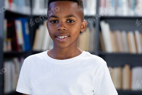 Preview: African american schoolboy wearing white t shirt with copyspace over library