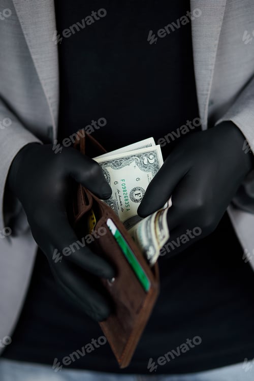 Preview: Man holding a wallet with money dollars in hand in black medical gloves.