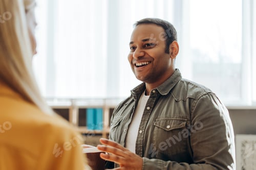 Preview: Indian businessman holding coffee cup talking with colleague in office
