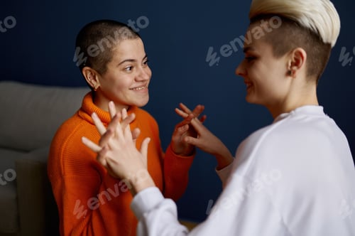 Preview: Happily smiling lesbian woman holding hands each other looking into eyes