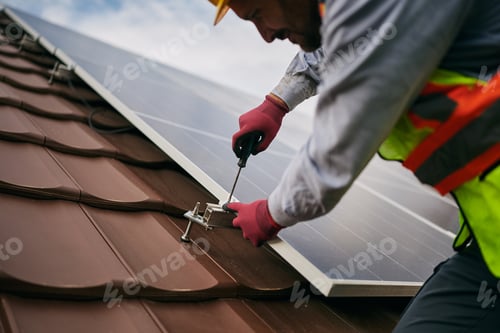 Preview: Close up of worker installing photovoltaic panels on solar system on the roof.