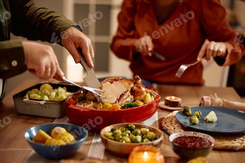 Preview: Cloe up of man carving roast turkey during Thanksgiving dinner in dining room.