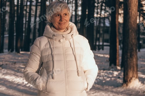Preview: Portrait of a happy middle-aged woman in winter in a snowy city park at sunset time. Winter vacation