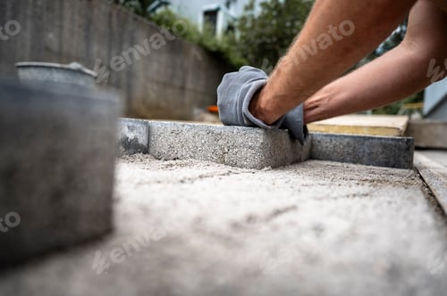 Preview: Worker laying concrete pavers for a patio