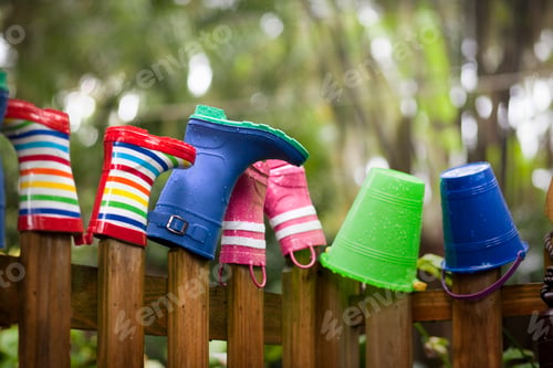 Preview: Row of rubber boots and buckets on top of garden fence