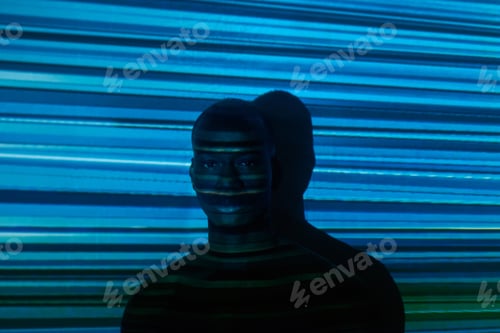 Preview: Serious young African man standing against wall with horizontal blue stripes