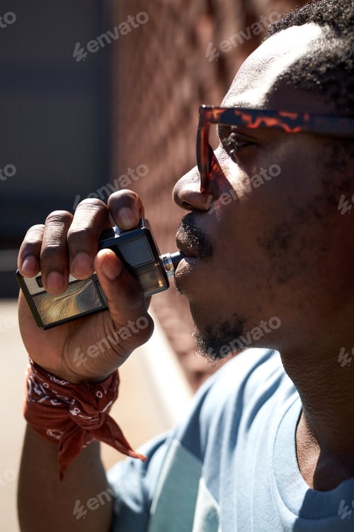 Preview: Close-up of young African American man with electronic cigarette in mouth