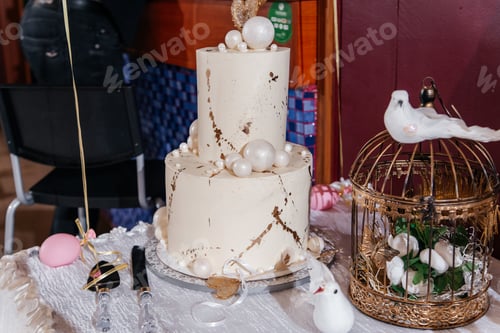 Preview: Golden-white wedding two-tiered cake on the table.