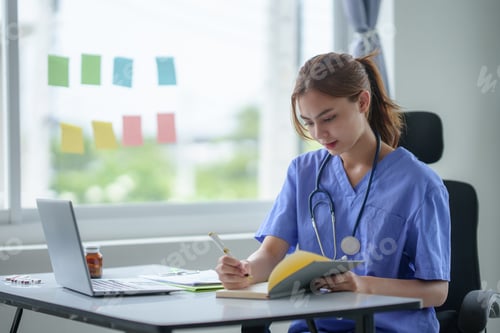 Preview: Attentive nurse in scrubs reviewing medical history or patient information on her laptop in office.