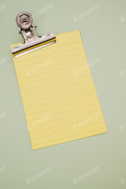 Preview: Vertical shot of a notepad and a paper clipper isolated on a gray background