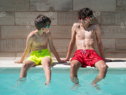 Preview: Two smiling kids sitting in a pool and enjoying the summer