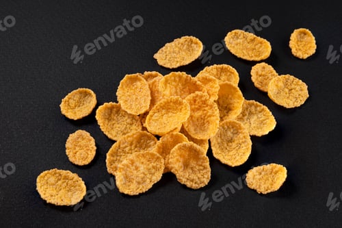 Preview: Corn flakes isolated on black background, top view