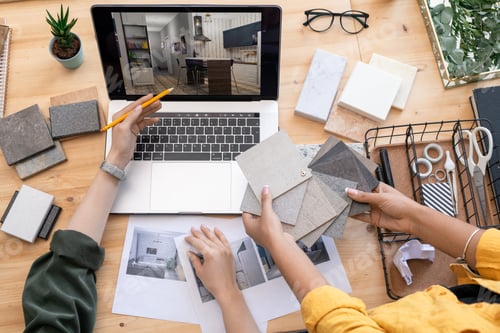 Preview: Contemporary designer pointing at home interior example on laptop display