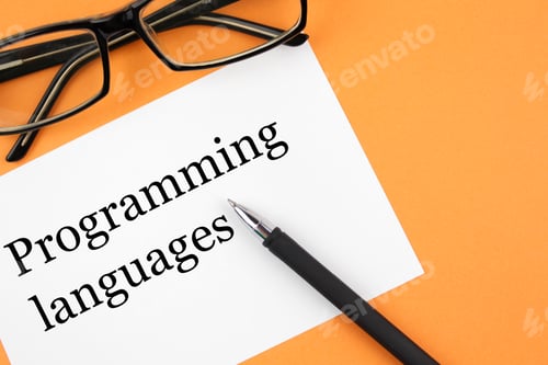 Preview: Reading glasses and blank with inscription programming languages on a orange background.
