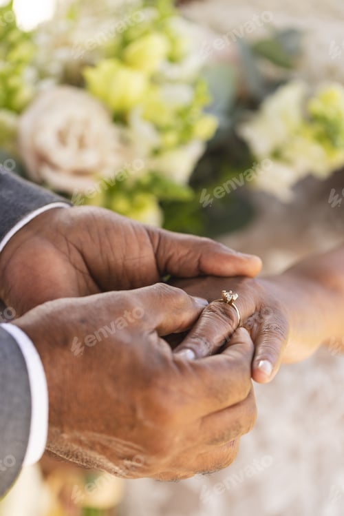 Preview: Hands of senior biracial groom putting wedding ring on finger of his bride