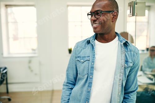 Preview: Young African businessman smiling while standing in a modern office