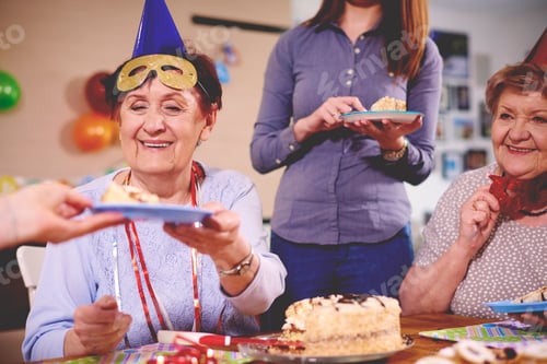 Preview: Senior women being served birthday cake at party