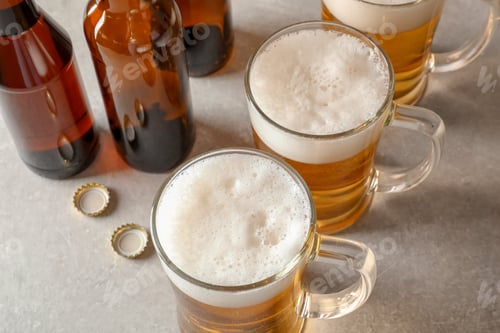 Vista previa: Glass mugs and bottles of cold tasty beer on table