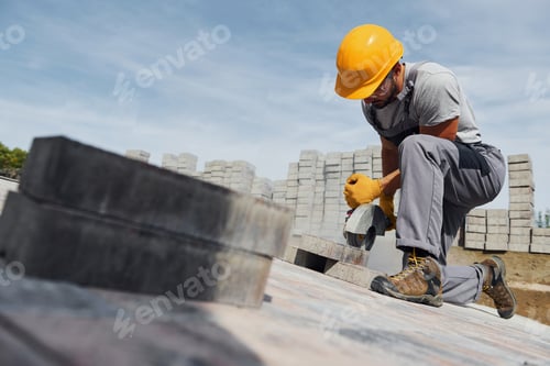 Preview: Concentrated at work. Man in yellow colored uniform have job with pavement