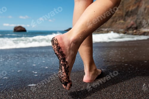 Preview: female feet walking on black sand beach