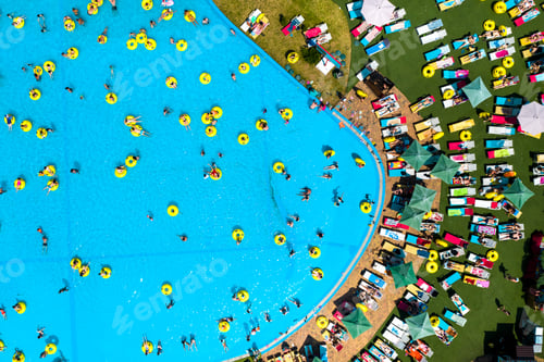 Preview: Top view of people relaxing in the pool on yellow inflatable circles and sun beds on the beach