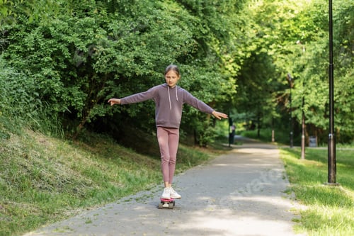 Preview: Child riding skateboard in sunny park path