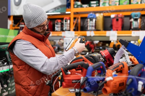 Preview: a customer in a non-power tool store chooses a new electric jigsaw for himself, the concept of a