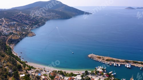 Preview: Aerial drone view of coastal town with green mountains.