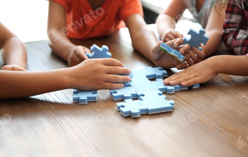 Preview: Little children playing with puzzle at table, focus on hands. Unity concept