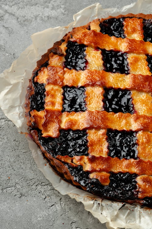 Preview: Freshly baked berry tart on a grey surface with a golden crust