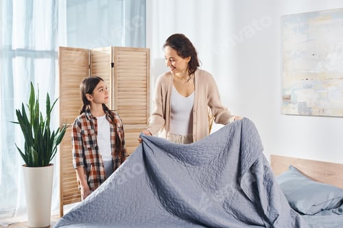 Preview: Serene mother and daughter by blue blanketed bed