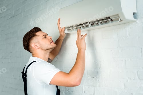 Preview: handsome installer looking at air conditioner