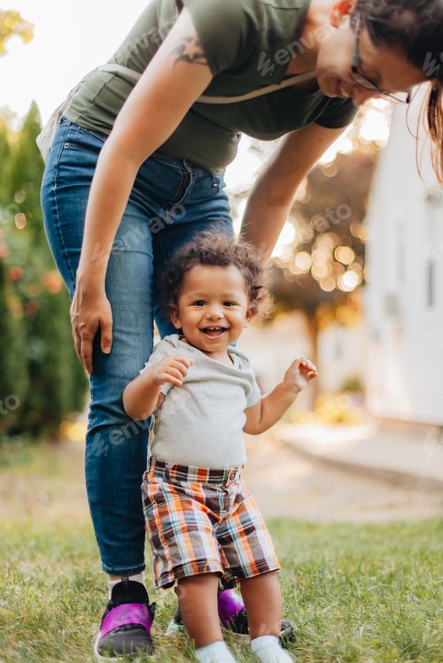 Preview: baby boy laughing while mother is aiding in his standing