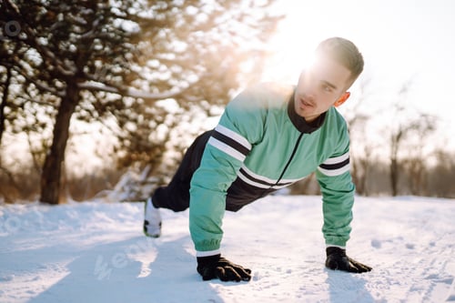 Preview: Young sportsman doing workout in forest at snowy winter day. Outdoor fitness, cardio exercises.