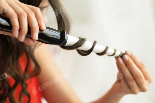 Preview: Hairstylist curling hair client in hairdressing salon