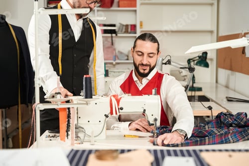 Preview: Apprentice tailor working in atelier under supervision of professional