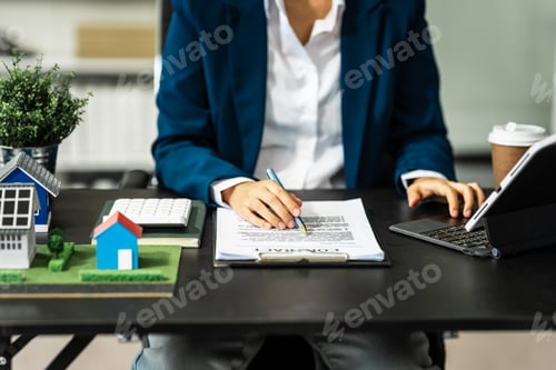 Preview: A businesswoman is reviewing contract papers at her desk in a sustainable house and condo