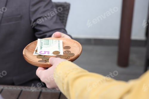 Preview: Client giving tips to waitress in outdoor cafe, closeup
