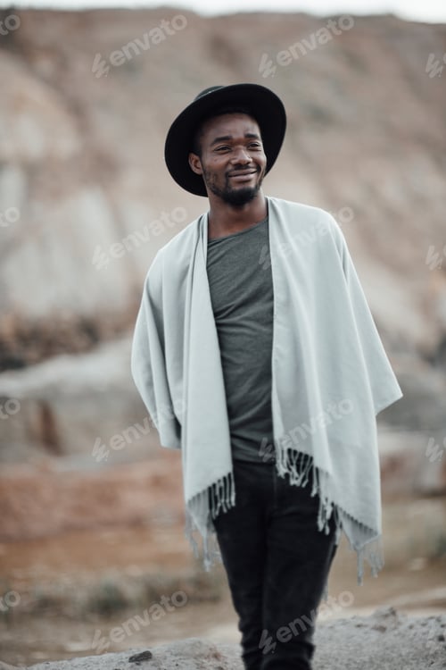 Preview: Handsome millennial black man in the desert in a black hat