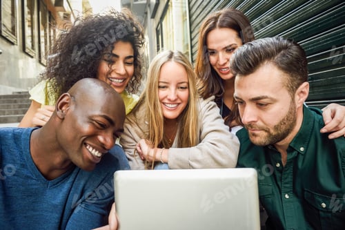 Preview: Multi-ethnic group of young people looking at a tablet computer outdoors in urban background. Group