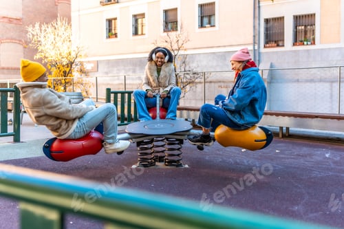 Preview: Young people having fun on a seesaw in winter city playground