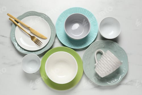 Preview: Beautiful ceramic dishware, cup and cutlery on white marble table, flat lay