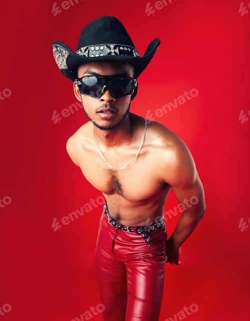 Preview: Fashion, man and cowboy in hat, shirtless with sunglasses and gen z isolated on red background. Con