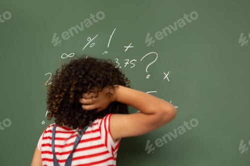 Preview: Schoolgirl trying to solve mathematics calculations on the green board in classroom at school