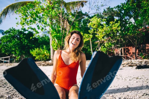 Preview: Young woman in flippers sitting on beach