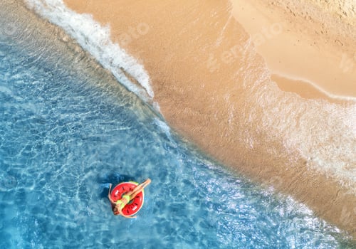 Preview: Aerial view of a young woman swimming with red swim ring