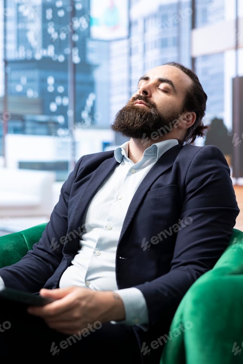 Preview: Stressed businessman sitting in his modern office and battling anxiety