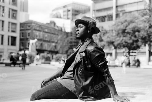 Preview: Relaxed man sitting on bench in the city in chromatic portrait.