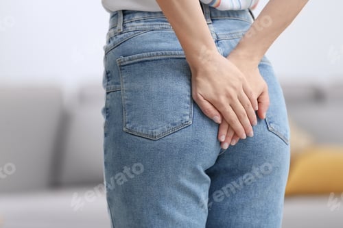 Preview: Young woman suffering from hemorrhoid at home, closeup